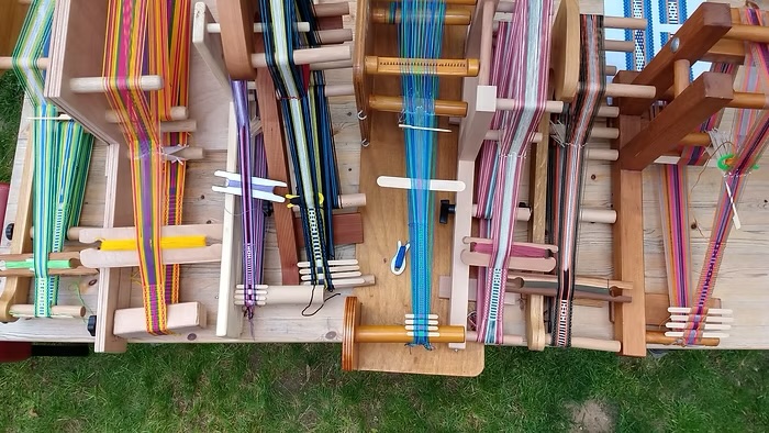 Several table looms displaying colorful woven bands created by participants during a beginner’s weaving workshop.